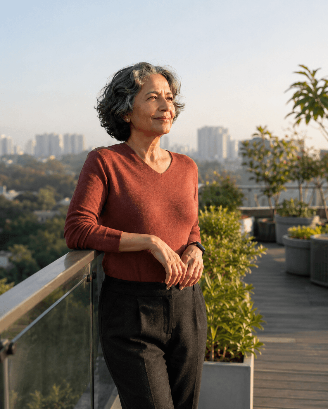 A confident Indian woman with natural silver hair enjoying the morning light on a rooftop garden